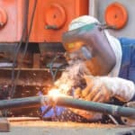 Welder working with welding equipment and safety gear in a welding supply shop environment