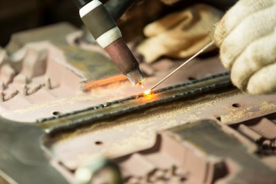 TIG welding torch creating a weld while filler rod is fed into the weld pool